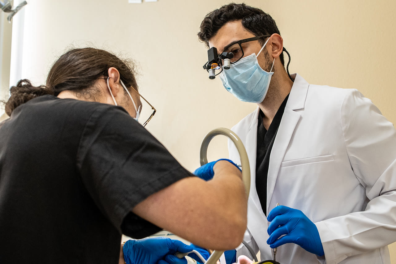Dr. Bani treating a patient with a dental assistant